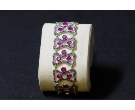 A silver, ruby and marcasite inlaid bracelet, set with 10 links of three rubies. Stamped 925.