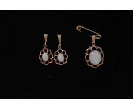 A gold and opal three piece earring and pendant set with pierced decoration.