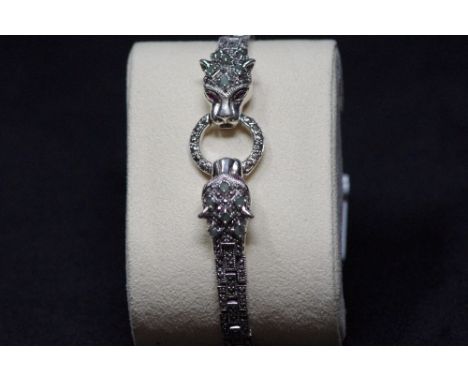 A decorative silver bracelet in the form of two leopards' heads, decorated with semi precious stones and ruby eyes.