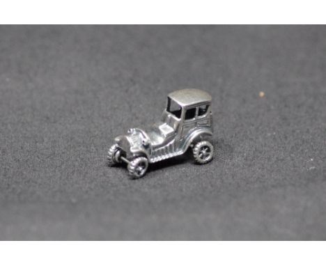 A silver trinket in the form of a vintage car. 