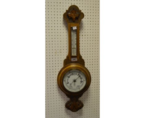 An early-20th century oak banjo barometer, carved with foliate scrolls throughout
