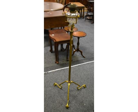 A Victorian wrought iron standard oil lamp, with telescopic action, clear glass reservoir, painted gold, circa 1880.
