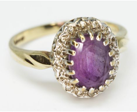 An amethyst and diamond cluster ring, the oval cut central stone approx. 8mm x 6mm, depth 4.66mm, hallmarked 9ct gold band, g