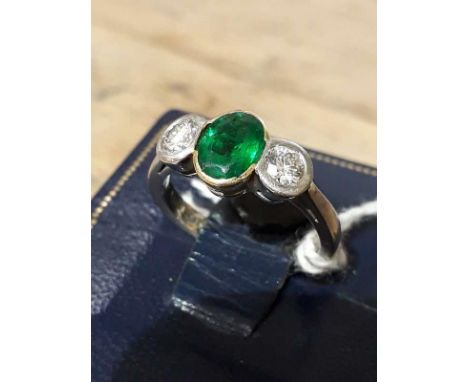 A diamond and emerald ring, the oval cut emerald measuring approx. 7.85mm x 6.10mm x 3.75mm, approx. wt. 1 carat, two round b