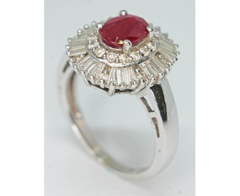 A contemporary Art Deco style ruby and diamond cluster ring, the oval cut ruby set within a surround of baguette and round br