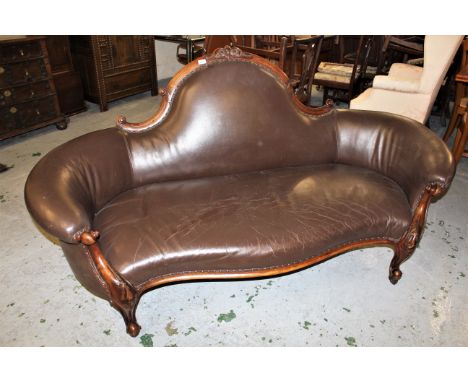 Victorian walnut sofa having carved crested back rail with brown leather upholstery, raised on carved cabriole front supports