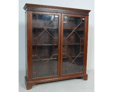 A late 19th century antique Victorian mahogany glazed bookcase display cabinet. The cabinet having carved top above twin astr