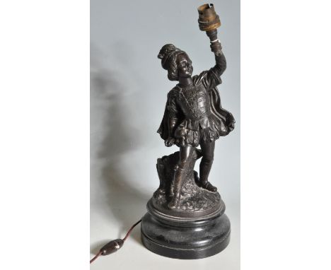 An early 20th century spelter lamp in the form of a boy holding the light set on a naturalistic base raised on a socle stand.