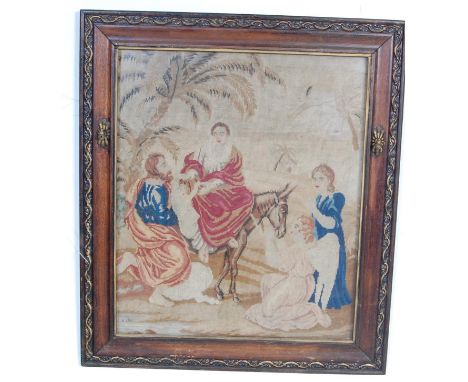 An antique early 20th century tapestry picture of a biblical scene having Jesus and Mary on a donkey with Joseph and an Angel