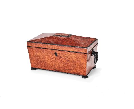 ϒ A large George IV amboyna and ebonised tea caddy, circa 1825, of sarcophagus form, the domed and hinged cover with gadroone