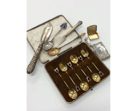 A cased set of six gilded metal teaspoons with blue enamel decoration and other silver and white metal items.