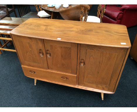 An Ercol sideboard fitted cupboard and smaller cupboard above draw resting on turned supports.