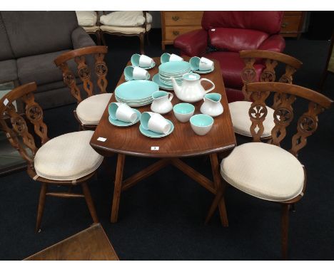 An Ercol drop leaf dining table resting on cross stretcher and square supports together with a set of four carved wheelback E