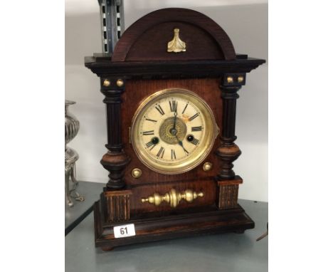 An oak cased mantle clock with circular dial, Roman Numerals.