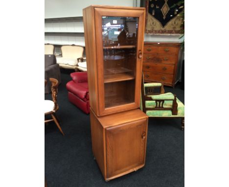 An Ercol display cabinet fitted single bevelled glass door to top and single panel door to base.