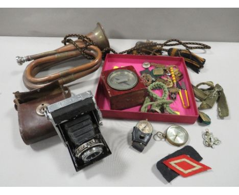 A tray of assorted militaria collectables to include a bugle, cap badges, etc