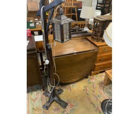 A oak drop leaf dining table together with a lantern style standard lamp