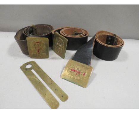 Three vintage leather military belts together with a brass button stick