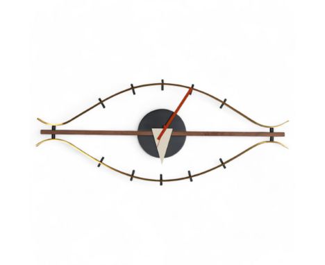A mid-century design wall clock in the form of an eye, the brushed brass frame curving around a walnut beam and central black