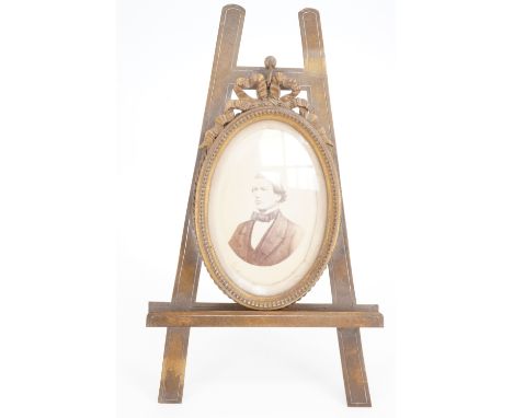 A Victorian brass photograph frame modelled as a ribbon-bow-surmounted oval frame on an easel-form stand, 21 cm