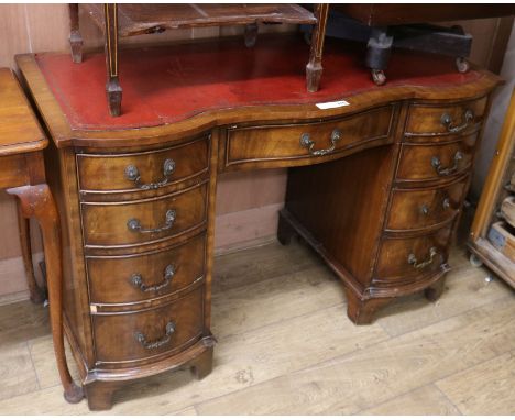 A reproduction Georgian style shape fronted mahogany twin pedestal desk, the top inset red leather, fitted three frieze drawe