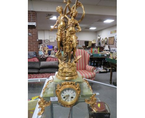 A GILT FIGURAL DECORATIVE MANTLE CLOCK WITH VARIEGATED ONYX BASED , THE FIGURAL SURMOUNT WITH LAMP CONVERSION