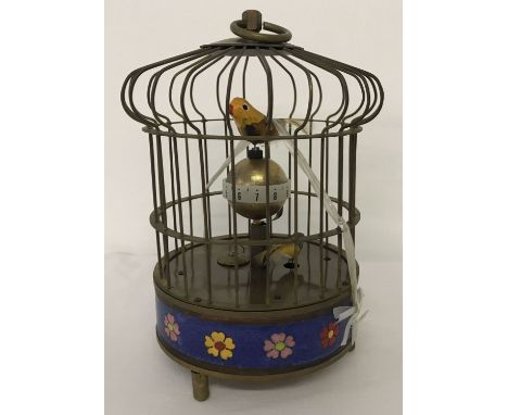 An ornamental wind up birdcage clock with cloisonné panel to base. The cage features two small feathered birds which rotate w