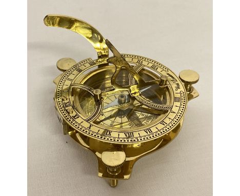 A brass sextant raised on screw adjustable height tripod feet. Marked West London. Approx. 9.5cm diameter.