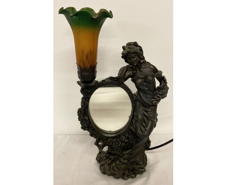 An Art Nouveau style resin table lamp with Tiffany style glass flower shade. Base has figure of a woman in flowing dress with