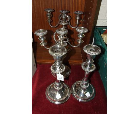 A pair of embossed plated copper three-light candelabra, 32cm high and a pair of plated candlesticks with beaded borders, 32c