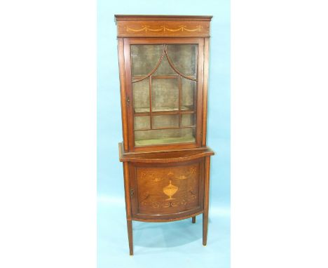 An Edwardian inlaid mahogany display cabinet, the upper section fitted with an astragal-glazed door above the bowed base with