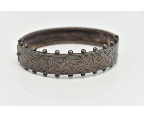 A MID CENTURY SILVER BANGLE, a Victorian style hinged bangle with etched foliage detail and beading edges, approximate width 