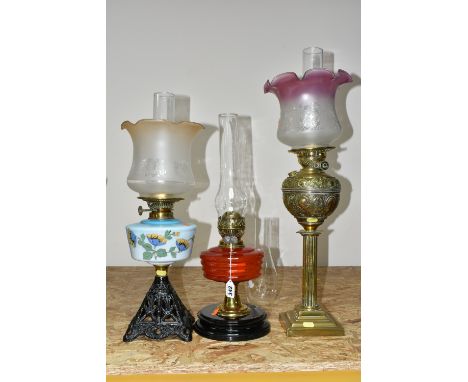 THREE LARGE VICTORIAN OIL LAMPS, comprising a cast pyramid shaped lamp base, with a blue custard glass reservoir hand painted