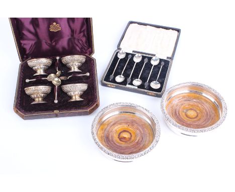 Silver: A cased set of four silver gilt salt bowls with embossed and engraved foliate decoration with four spoons by Jay Rich