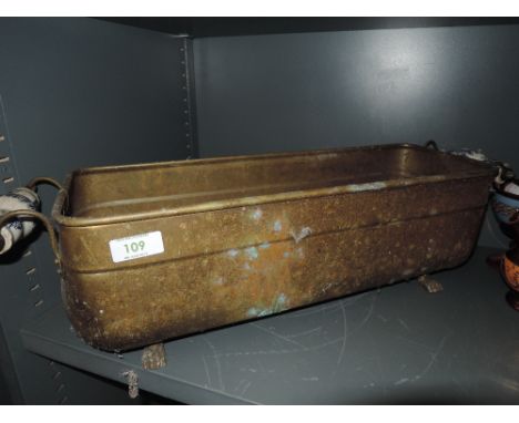 A brass trough planter with ceramic handles 