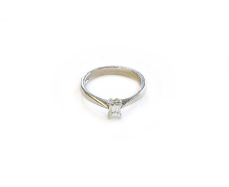 A Platinum Diamond Solitaire Ring, the emerald cut diamond in a four claw setting, to a tapered shoulder plain polished shank