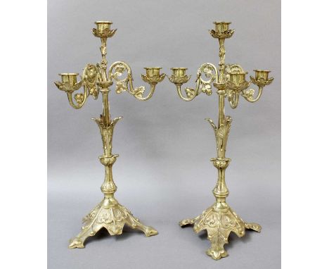 A Pair of Gilt Brass Four Light Candelabra, on stylised leaf moulded bases; together with a similar three-light wall sconce o