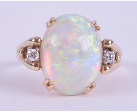 A 14ct yellow gold ring set with a central oval cabochon cut white opal, measuring approx. 15.9mm x 11.5mm with a small round