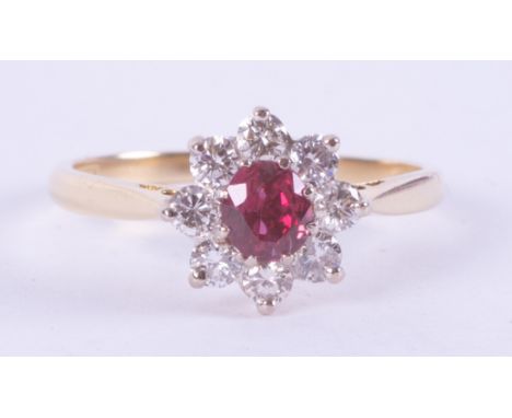 An 18ct yellow gold ring in a flower design set with a central round cut ruby, measuring approx. 0.44 carats surrounded by ro