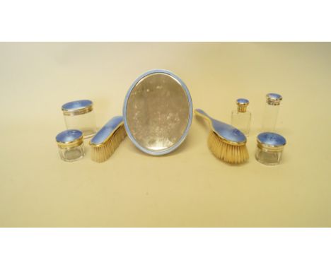 A silver gilt and blue guilloche enamel dressing set, by Cole Brothers, London 1922; comprising oval easel mirror; five vario