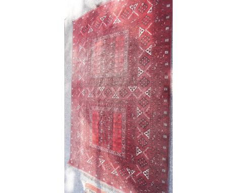 An Afghan red ground rug having two central panels, 230 x 160cm.
