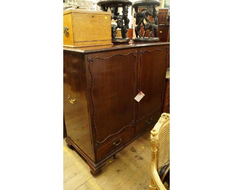 A George III mahogany linen press, the pair of moulded panel doors enclosing four sliding trays above a pair of apron drawers