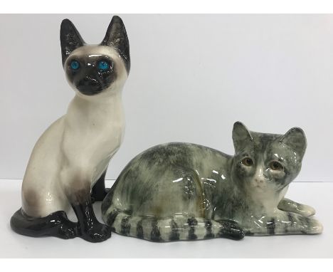 A Winstanley Pottery cat in grey/green tones lying down, signed "I Winstanley", 33 cm long, together with a Kensington Potter