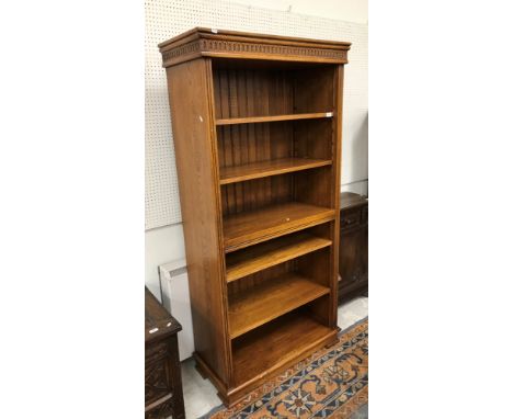 A 20th Century oak open bookcase in the 18th Century style, the moulded and notch carved cornice over two banks of adjustable