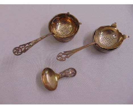 A silver caddy spoon and two silver tea strainers with stands