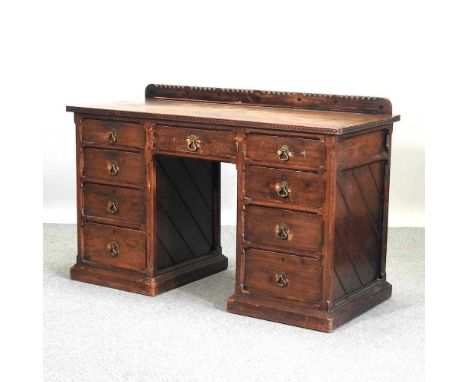 A 19th century Arts and Crafts pitch pine pedestal desk, with a galley back, containing nine short drawers, with chamfered an