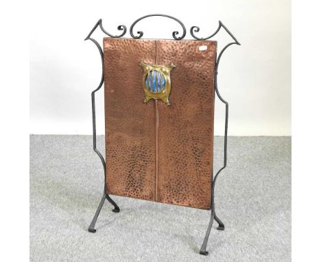 An Arts and Crafts copper, brass and wrought iron firescreen, the hammered copper panel inset with a Ruskin style blue enamel