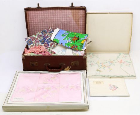 A vintage suitcase containing table wares to include cloths, napkins, place mats and linen.