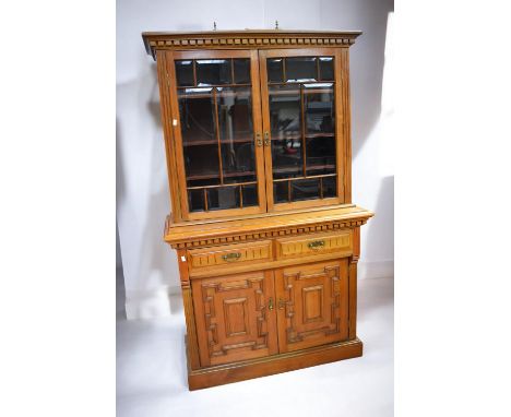 A Victorian light oak display/bookcase cupboard with glazed front top doors above two drawers and two cupboard doors.