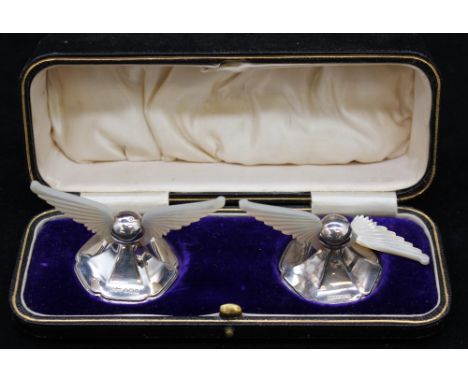 A pair of Edwardian silver and mother of pearl knife rests, the mother of pearl carved as wings, on weighted hexagonal sectio